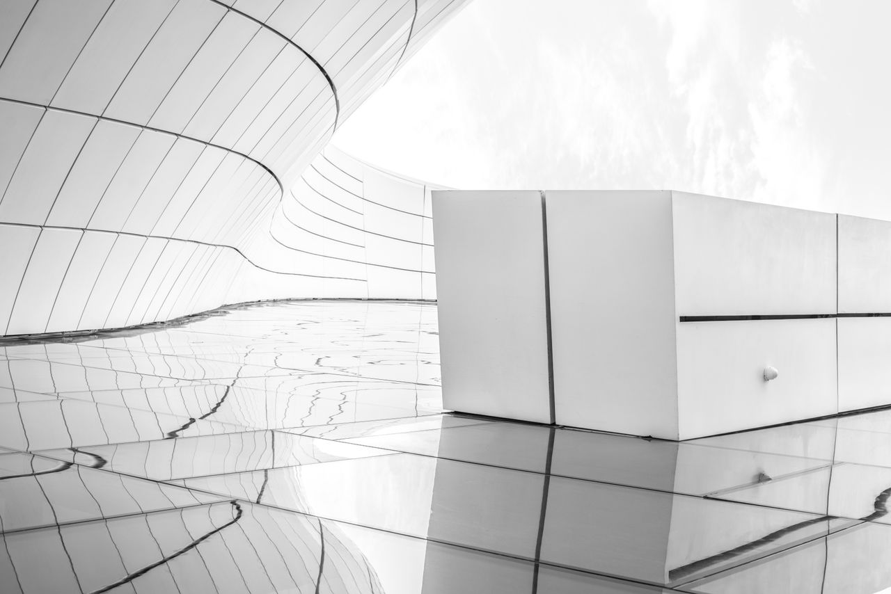services-bg Sleek futuristic architecture in black and white with reflective surfaces.