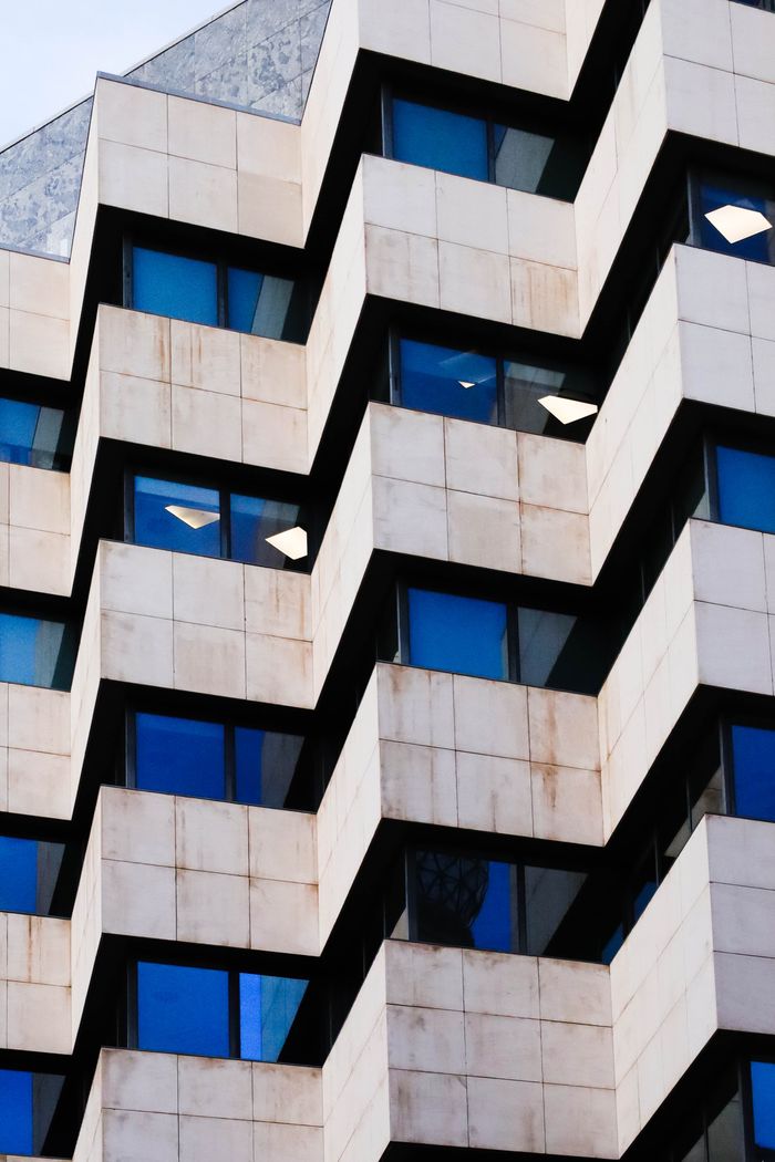 services-02 Dynamic view of a modern building with zigzag geometric designs and blue windows.